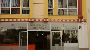 Entrada de hotel con un letrero que dice 'Welcome', puertas de vidrio y un área de descanso en el interior.