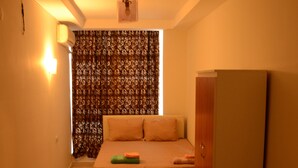 Una habitación pequeña y tenuemente iluminada con una cama, un armario y una cortina.