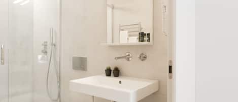 Un baño moderno con cabina de ducha de vidrio, un lavabo blanco y un espejo sobre el lavabo.