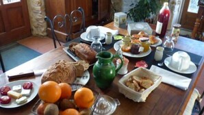 A breakfast table with various food items, a green pitcher, and a bottle of juice.
