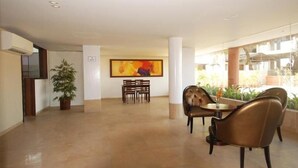 Una habitación amplia con comedor, una mesa y sillas, un cuadro abstracto grande en la pared y una planta en maceta.