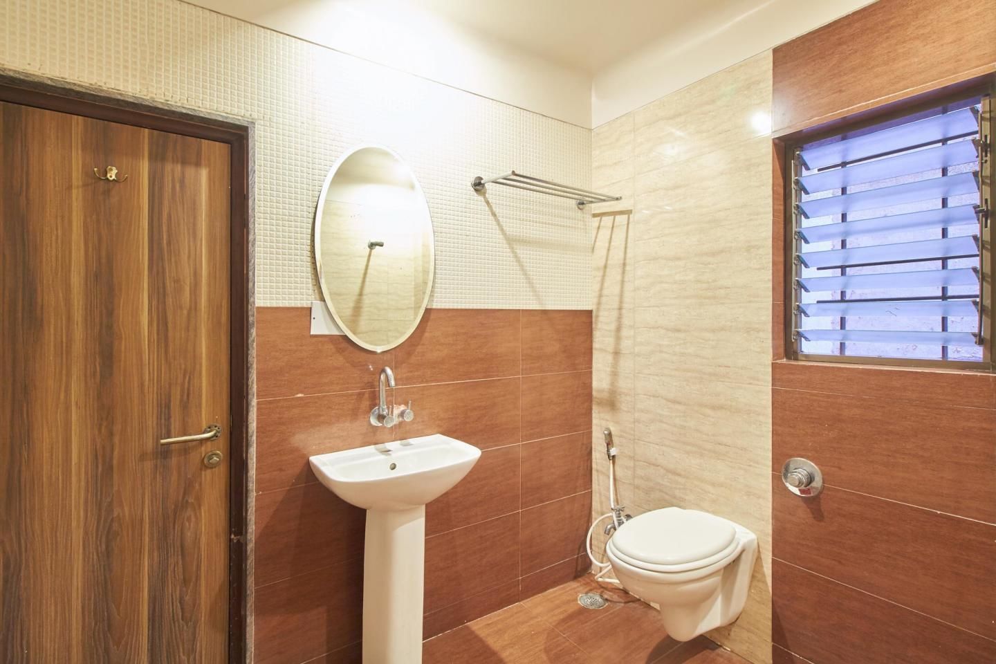 A bathroom with a wooden door, a white sink, a toilet, and a shower area.