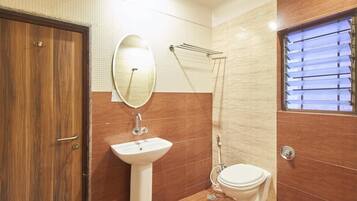 A bathroom with a wooden door, a white sink, a toilet, and a shower area.