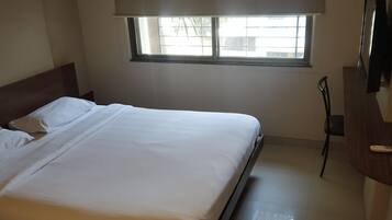 Een hotelkamer met een bed, een raam, een televisie en een bureau.
