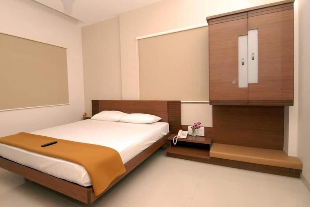 A bedroom with a bed, a bedside table with a phone, and a wooden wardrobe.