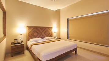 A hotel room with a wooden headboard, a bed with white linens, a nightstand with a lamp, and a large window.