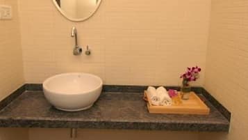 Un baño con un espejo redondo, un lavabo blanco, un inodoro y un perchero con toallas dobladas.