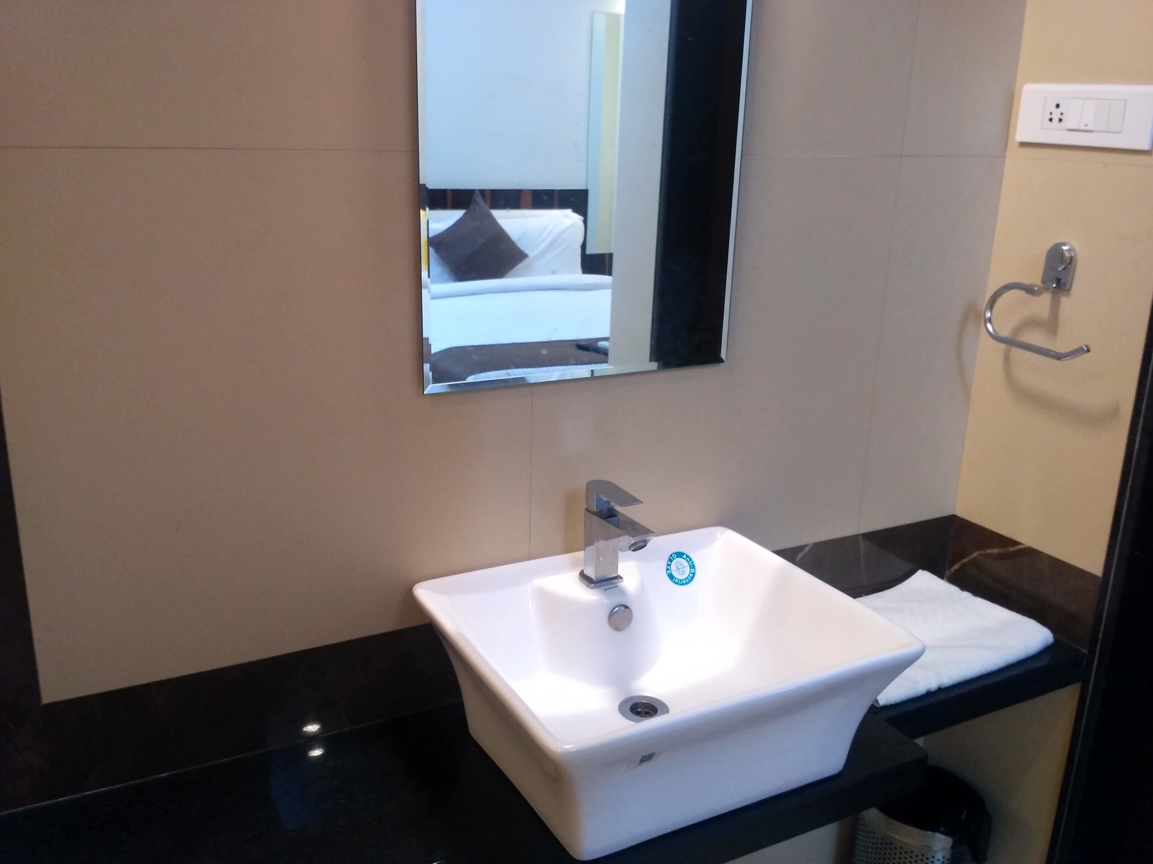 A bathroom with a white sink, a mirror, and a towel rack.