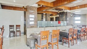 Un comedor amplio con sillas y mesas de madera, un área de estar central con un sofá y un diseño de techo moderno.