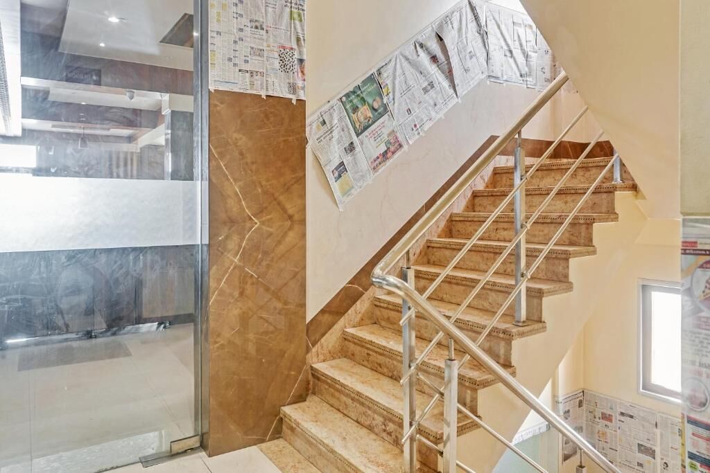 Un escalier avec une rampe en métal, une porte en verre et des journaux accrochés au mur.