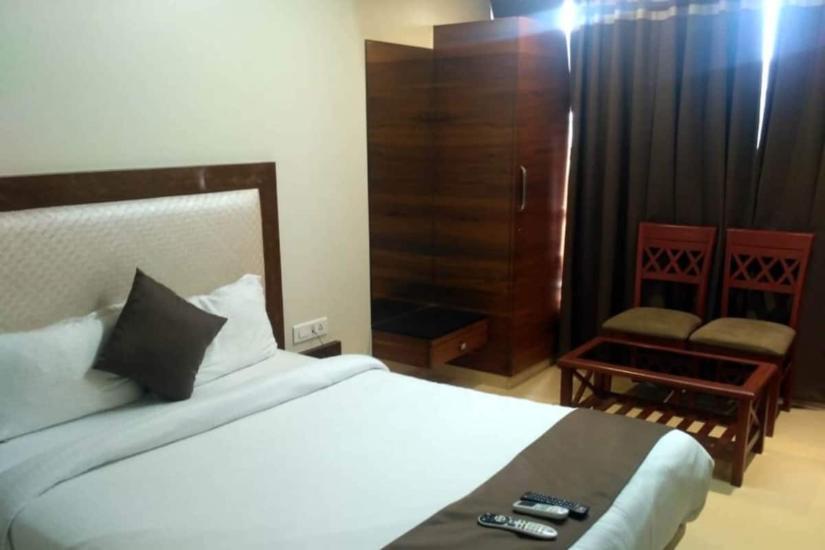 Ein Hotelzimmer mit Bett, Schrank, Sitzecke und Fernbedienung auf dem Bett.