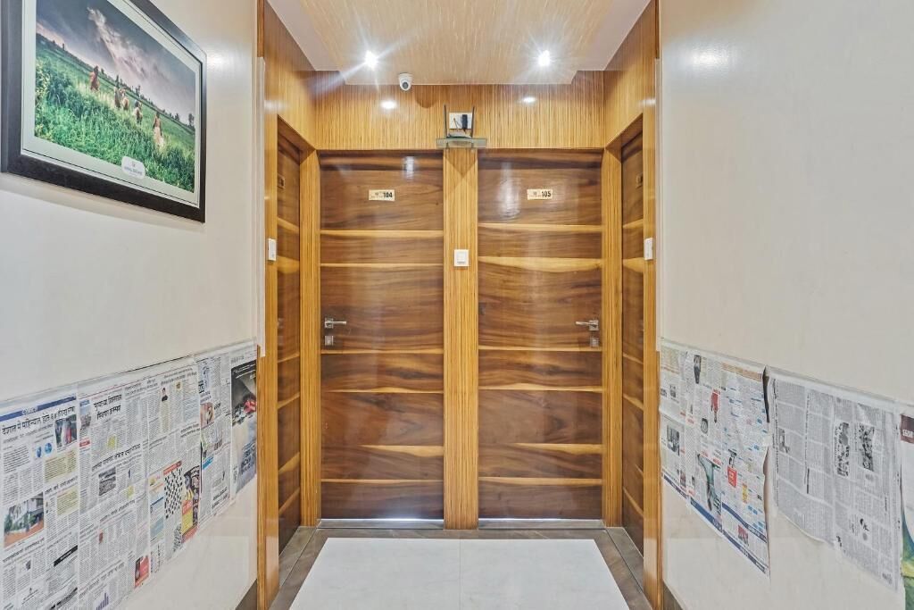 A hallway with wooden double doors, a security camera, and newspapers on the walls.