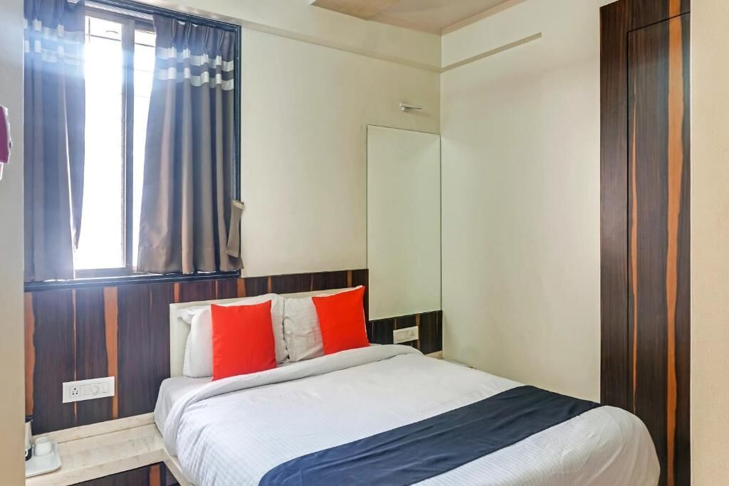 Una habitación de hotel con cama, mesita de noche, espejo y armario.