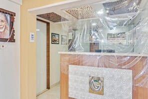 Zona de recepción con pared de diseño, mostrador de madera y techo decorativo.
