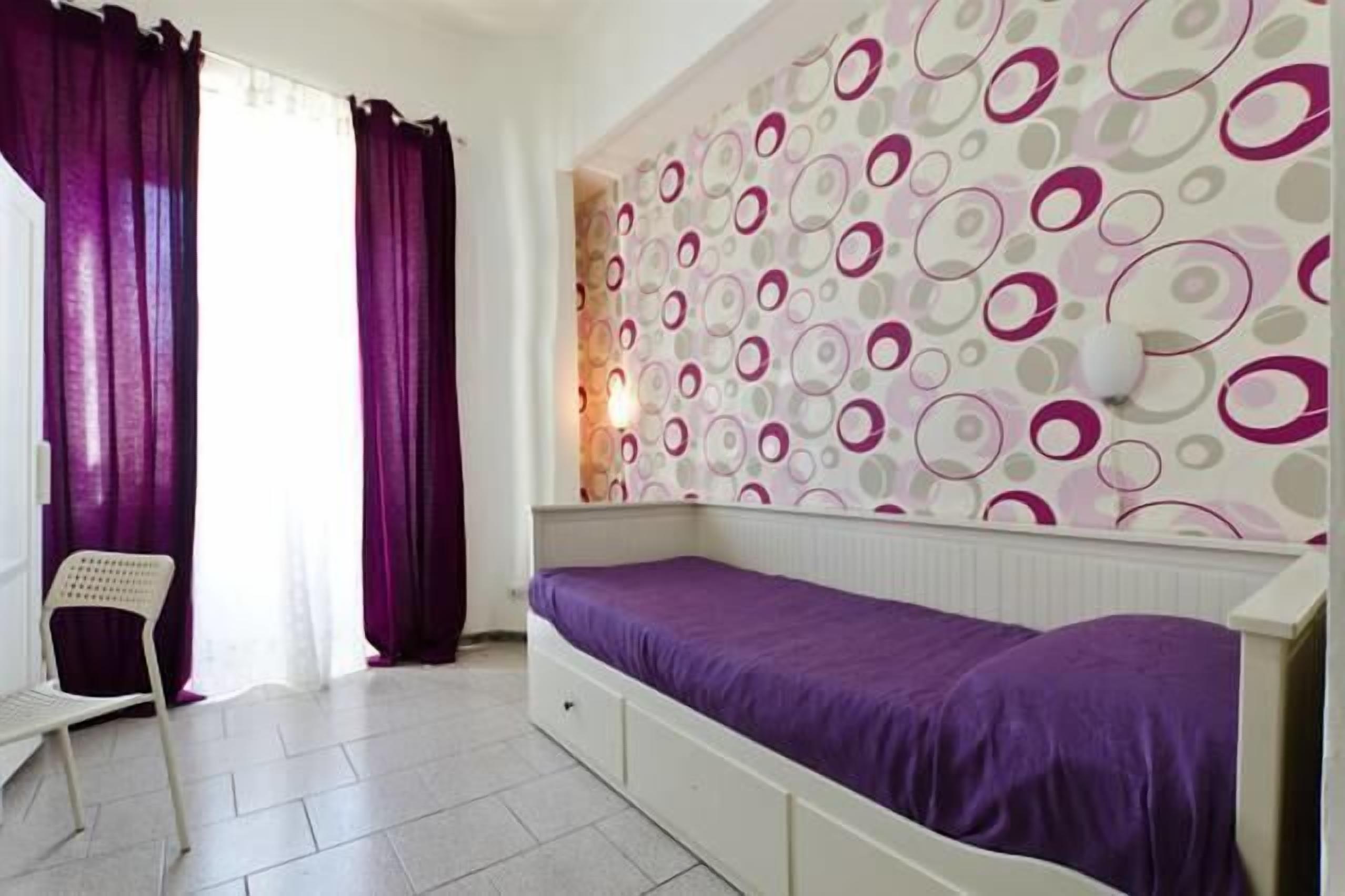 Ein Zimmer mit einem Bett, einem Sessel und einer Wand mit kreisförmigen Mustern.