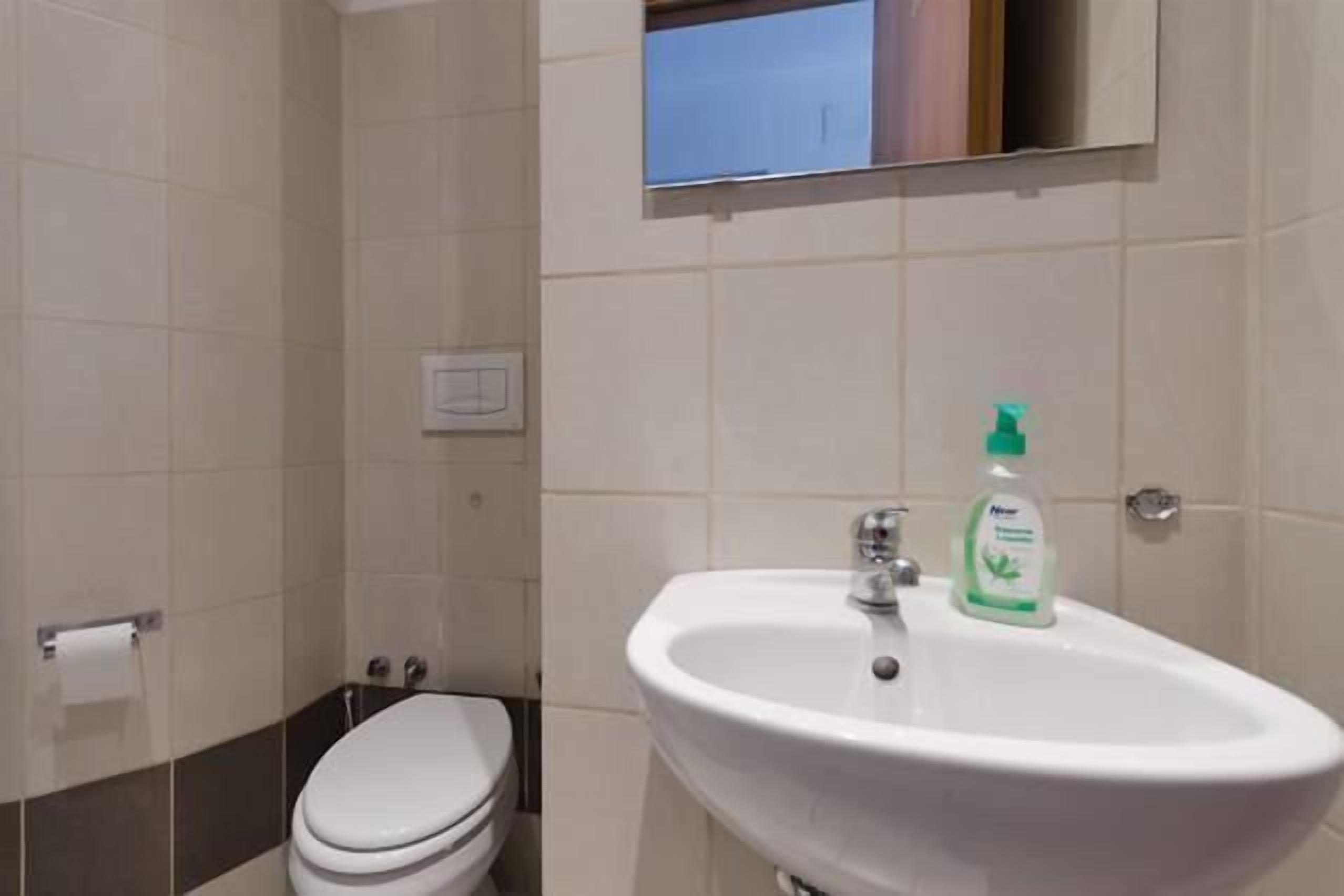 Et badeværelse med en hvid vask, et spejl og et toilet.