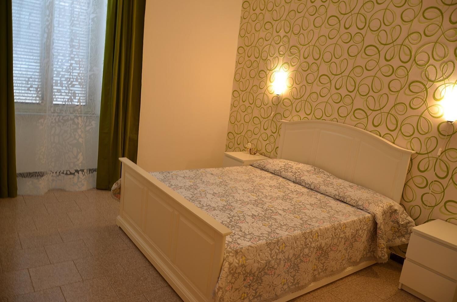A bedroom with a bed, a nightstand, and a wall with a circular pattern.