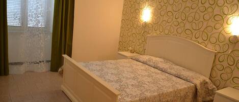 A bedroom with a bed, a nightstand, and a wall with a circular pattern.