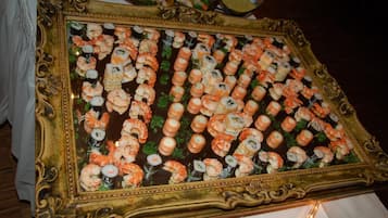 Uma grande e ornamentada travessa de sushi dourada, com diversos tipos de sushi, incluindo camarão e enrolados, sobre uma mesa.