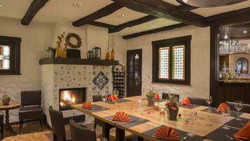 A dining area with a fireplace, a long table set for four, and a wine rack in the background.