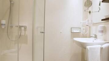Un baño moderno con cabina de ducha de vidrio, lavamanos y espejo.