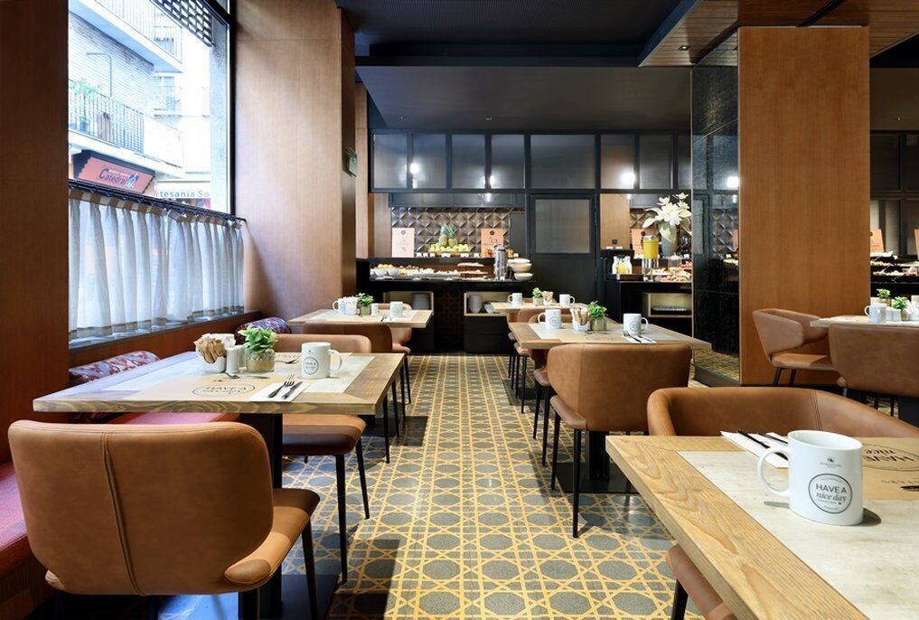 A restaurant with a patterned floor, wooden tables, and leather chairs.