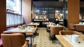 A restaurant with a patterned floor, wooden tables, and leather chairs.