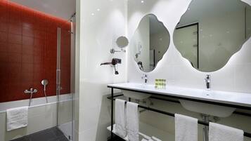 Un baño moderno con cabina de ducha de vidrio, un lavamanos blanco con encimera negra y dos espejos grandes en la pared.