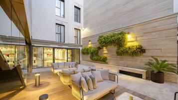 Un área de estar moderna al aire libre con un sofá y sillones, una mesa de centro y un jardín vertical con plantas.