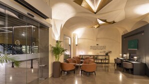A modern hotel lobby with a reception desk, seating area, and a large potted plant. - Áurea Catedral by Eurostars Hotel Company (Granada)