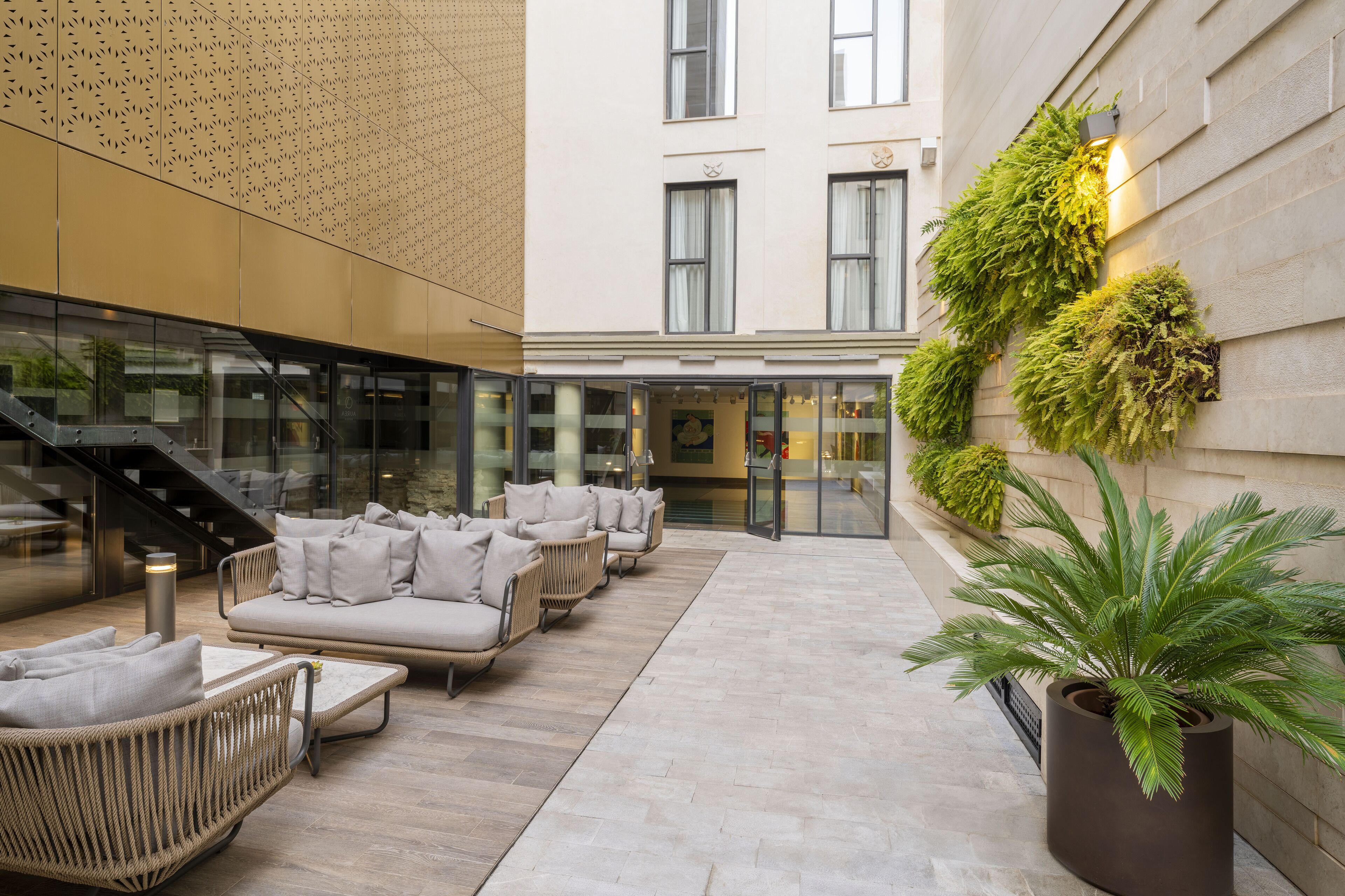 A modern outdoor seating area with wicker furniture and a large potted plant.