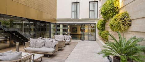 A modern outdoor seating area with wicker furniture and a large potted plant.