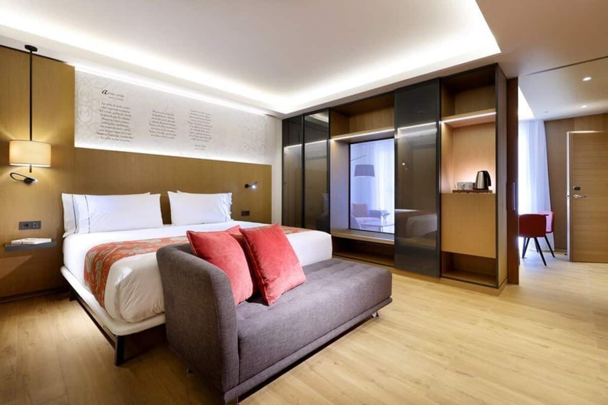 Ein modernes Hotelzimmer mit Bett, Sofa, Schreibtisch und Kleiderschrank.