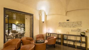 Un vestíbulo con sillones de cuero, una pequeña mesa redonda, una consola con objetos decorativos y una pared con una cita.