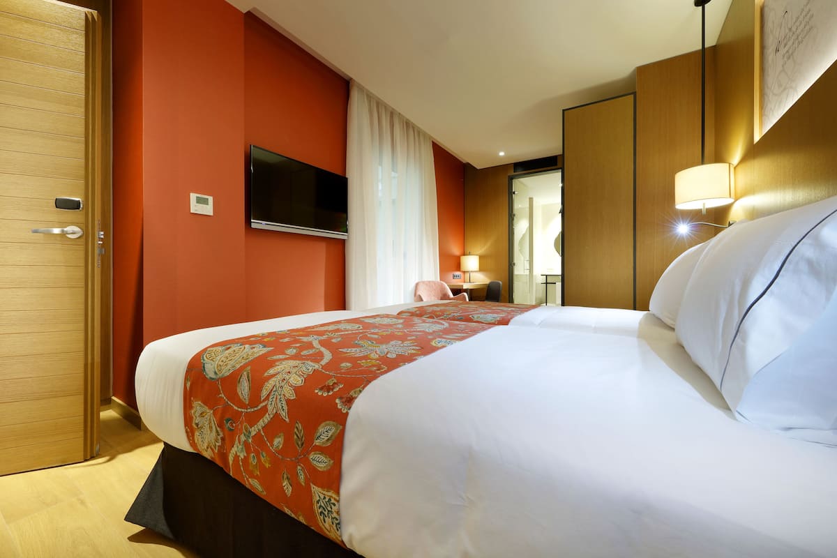 Ein Hotelzimmer mit einem großen Bett, einem an der Wand befestigten Fernseher und einer Holztür.