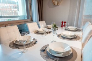 A dining table set with plates, glasses, and cutlery, with a view of a building outside.