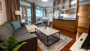 A modern living room with a sofa, coffee table, and a dining area with a table and chairs.