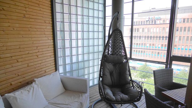 A room with a white sofa, a hanging chair, and a table.