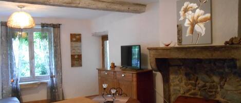 Una sala de estar acogedora con chimenea de piedra, muebles de madera y un televisor sobre un soporte de madera.