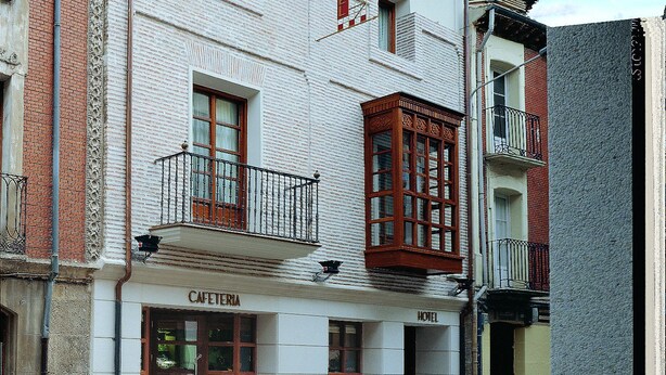 Un edificio de dos plantas con una cafetería en la planta baja y un hotel en la superior.