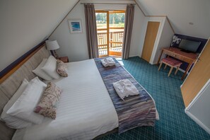 Un dormitorio con cama, escritorio, silla y televisor.
