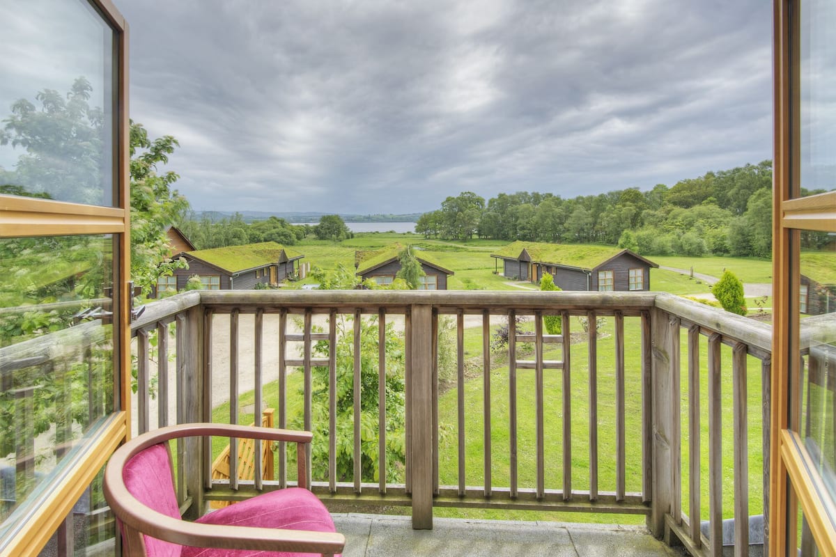 A balcony with a view of a green landscape and small houses.