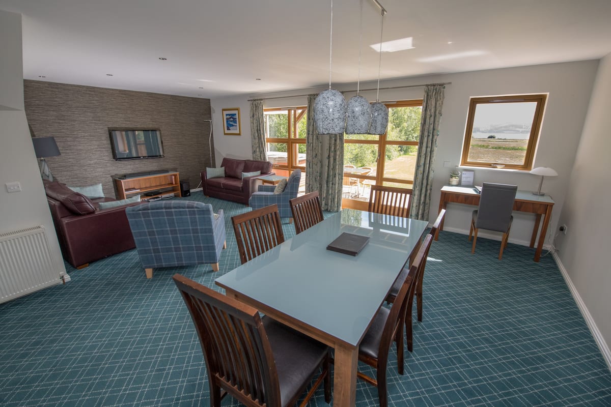 A spacious living area with a dining table, chairs, a sofa, and a TV.