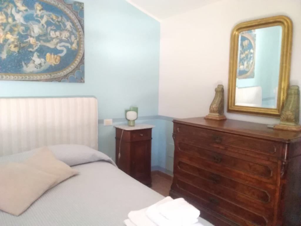 Un dormitorio con cama, cómoda, espejo y un adorno en la pared.