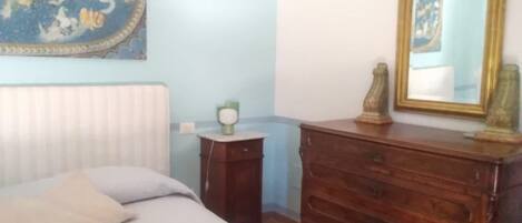 Un dormitorio con cama, cómoda, espejo y un adorno en la pared.
