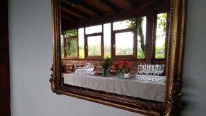 A dining table set with glassware and a vase of flowers, framed by an ornate mirror. - Gli Archi (Fauglia)