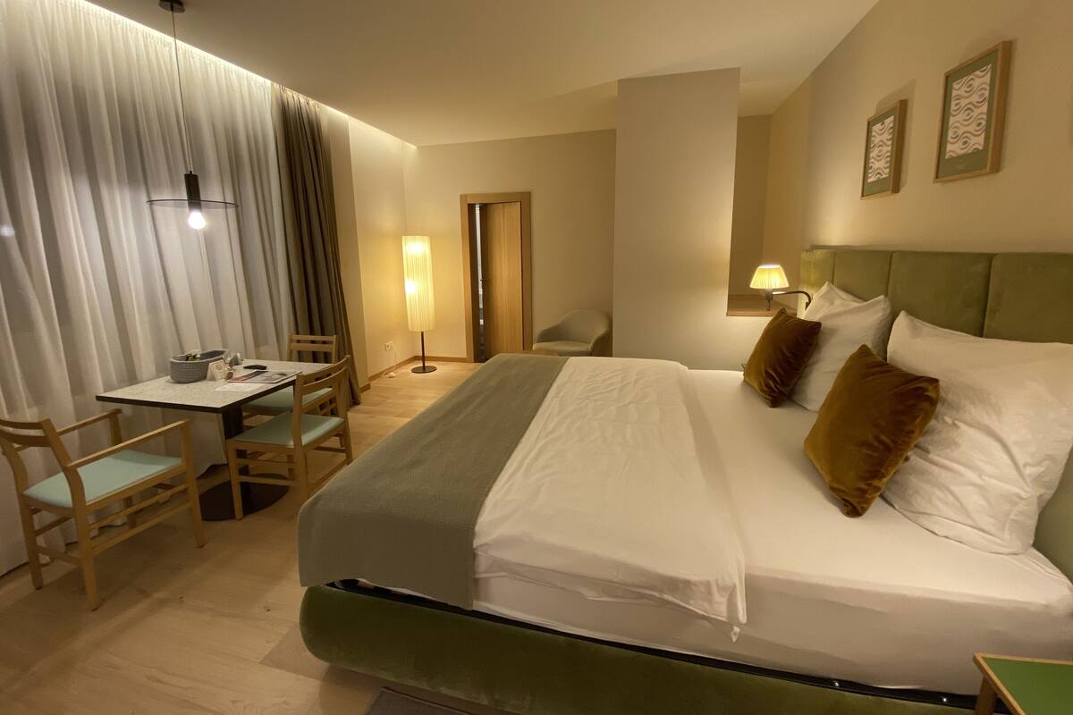 Hotellihuone, jossa on sänky, työpöytä, tuoli ja lamppu.