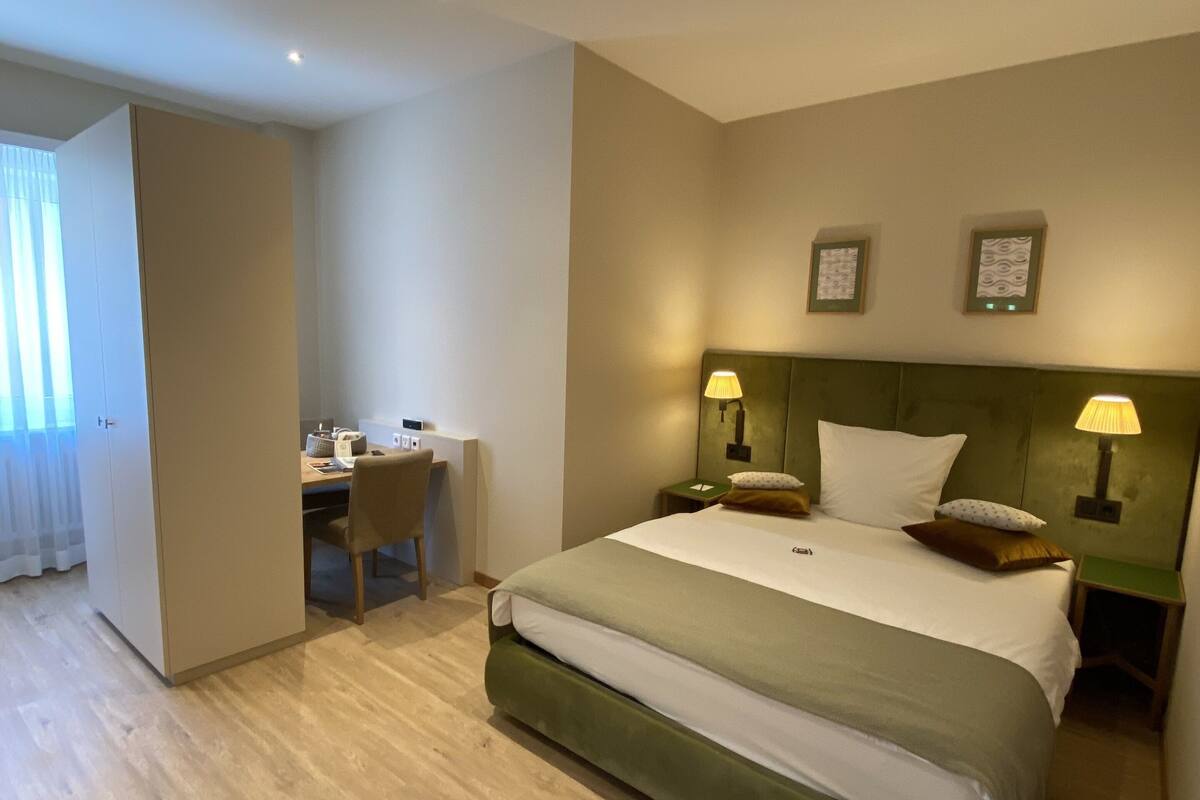 Hotellihuone, jossa on sänky, työpöytä ja tuoli.