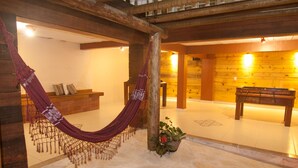A wooden interior with a hammock, a bench, and a small table. - Pousada Solar de Geribá (Búzios)