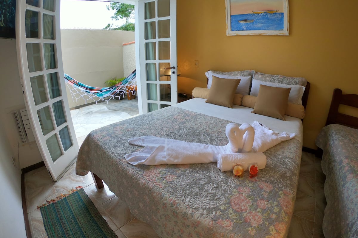 Une chambre d’hôtel avec un lit, un hamac et un tableau au mur.